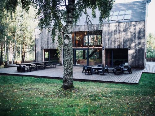 une maison avec des tables et des bancs sur une terrasse dans l'établissement Cisowy Zakątek, à Sasino