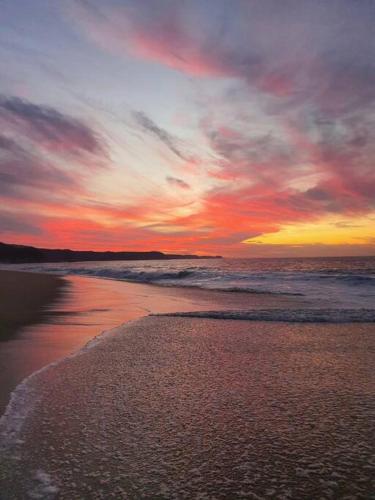 a sunset on a beach with the ocean at Gotita in Yolina