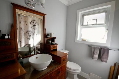 a bathroom with a sink and a toilet and a window at The Orange Door Bungalow in Vancouver