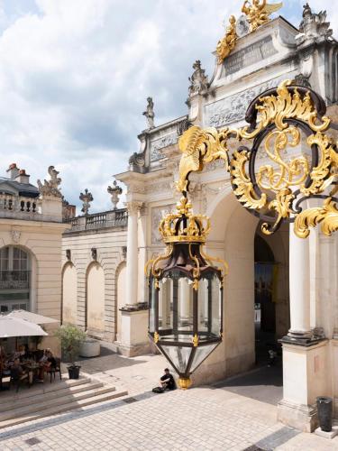 un grand bâtiment doré et blanc avec un lampadaire dans l'établissement Sur la place Stanislas, à Nancy