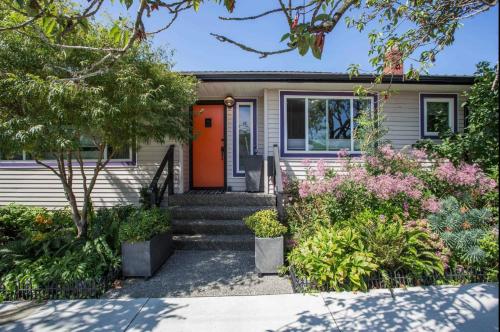 a house with an orange door and some plants at The Orange Door Bungalow- 2-BR w private yard, walkable to cafes & restaurants, 10 min to DT in Vancouver
