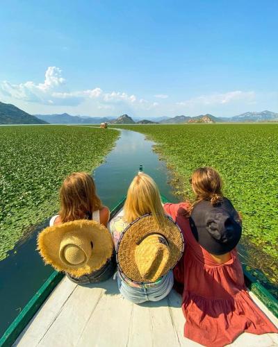 three girls sitting on a boat looking at a river at Apartments FLORA and boat cruising in Virpazar