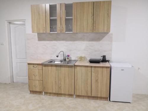 a kitchen with wooden cabinets and a sink and a refrigerator at Apartman MAJ in Bijelo Polje