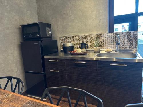 eine Küche mit einer Spüle, einer Mikrowelle und einem Kühlschrank in der Unterkunft Marna family - Vacation STAY 69396v in Takaoka