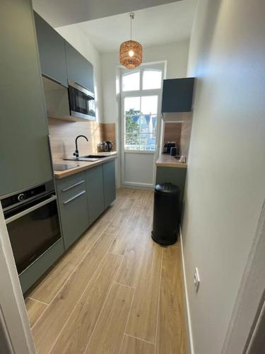 Il comprend une cuisine avec des placards verts et du parquet. dans l'établissement Belle maison berckoise rénovée - LM la plage, à Berck-sur-Mer