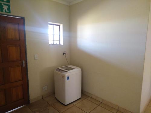 a bathroom with a small window and a trash can at KUNGWINI ACADEMY CENTRE in Erasmus