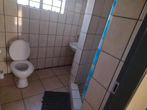 La salle de bains est pourvue de toilettes et d'un mur carrelé. dans l'établissement KUNGWINI ACADEMY CENTRE, à Bronkhorstspruit