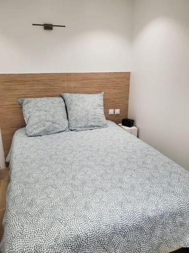 une chambre avec un grand lit avec une tête de lit en bois dans l'établissement T2 neuf indépendant dans villa proche des plages, à La Seyne-sur-Mer