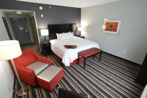 a hotel room with a bed and a red chair at Hampton Inn & Suites Albany at Albany Mall in Albany