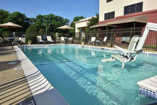 a large swimming pool with a chair and chairs in a hotel at Hampton Inn & Suites Alexandria in Alexandria