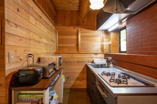 cocina con paredes de madera y horno con fogones en Log house Grazzi - Vacation STAY 70263v, en Nasu-yumoto