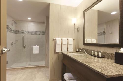 a bathroom with a shower and a sink and a mirror at Embassy Suites Saratoga Springs in Saratoga Springs