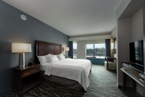 a hotel room with a bed and a television at Embassy Suites Saratoga Springs in Saratoga Springs