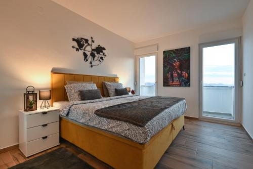 a bedroom with a large bed and two windows at Apartman Nella with sea wiew in Zadar