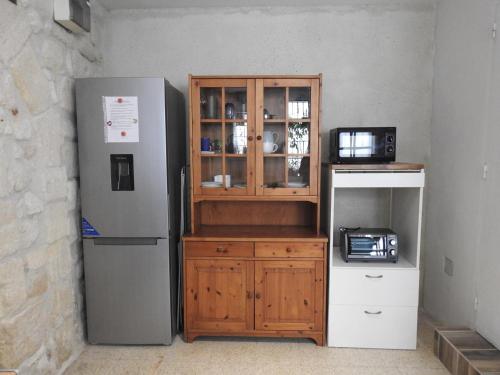 una nevera y un armario de madera junto a un microondas en Appart' Cosy Beaucairois, en Beaucaire