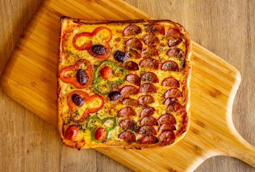 a pizza sitting on top of a wooden cutting board at Laghetto Canela in Canela