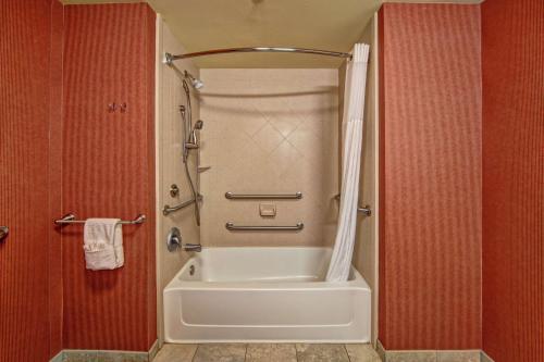 a bathroom with a shower and a white bath tub at Hampton Inn Jacksonville in Jacksonville
