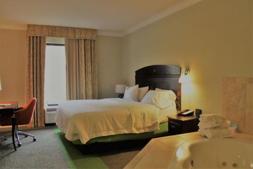 アメリカスにあるHampton Inn Americusのベッドとバスタブ付きのホテルルームです。