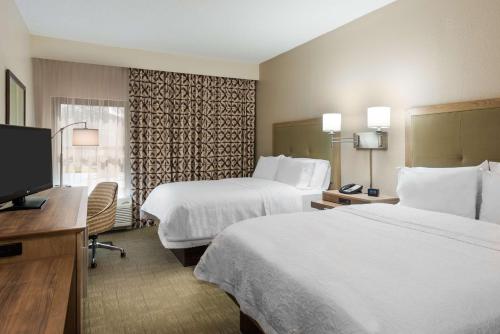 a hotel room with two beds and a flat screen tv at Hampton Inn Bonita Springs Naples North in Bonita Springs