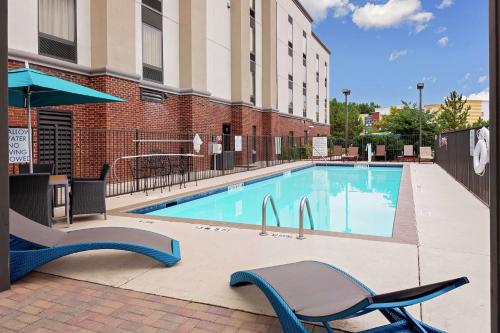 a swimming pool with two chairs and a building at Hampton Inn Atlanta-Fairburn in Fairburn