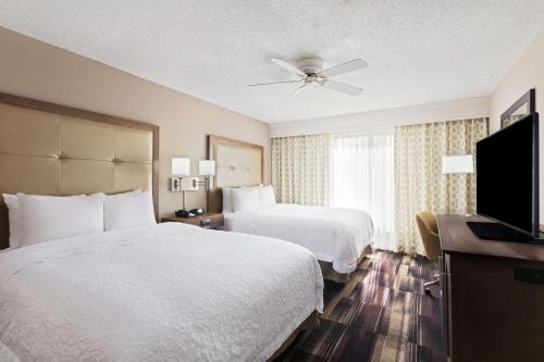 a hotel room with two beds and a flat screen tv at Hampton Inn & Suites Atlanta/Duluth/Gwinnett in Duluth