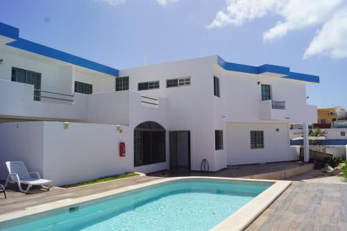 a white house with a swimming pool in front of it at Hotel La Trigueña in Isla Mujeres