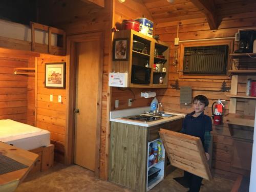 Un ragazzo in piedi in una cucina in una cabina di Cabin 1. For freedom loving simple not picky people. Rental cars available. a Custer