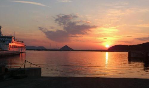 a boat is docked at a dock with the sunset at Yado Seven Beach in Naoshima
