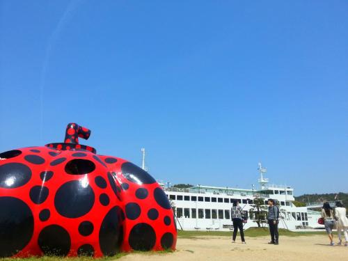 a large lady bug sculpture in front of a ship at Yado Seven Beach in Naoshima