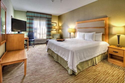a hotel room with a bed and a flat screen tv at Hampton Inn & Suites Kalamazoo-Oshtemo in Oshtemo