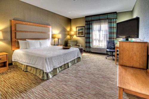 a hotel room with a bed and a flat screen tv at Hampton Inn & Suites Kalamazoo-Oshtemo in Oshtemo