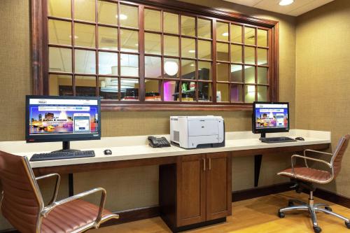 a desk with two computer monitors and a printer at Hampton Inn Bedford in Bedford