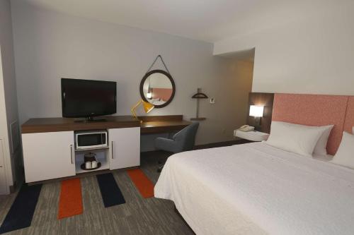 a hotel room with a bed and a flat screen tv at Hampton Inn Owego in Owego