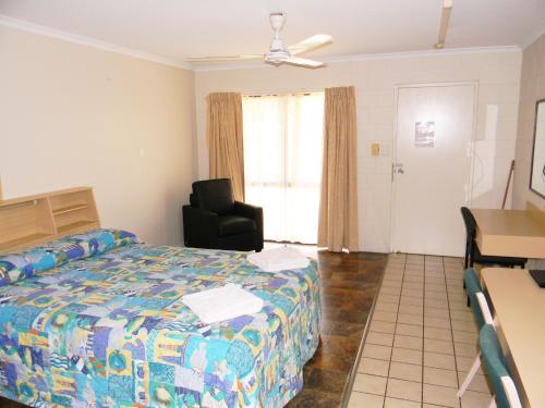 1 dormitorio con cama, silla y escritorio en Rover Motel, en Mackay