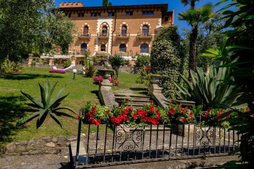 a house with flowers in front of a fence at Hotel Bellevue in Gardone Riviera