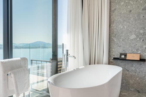 a white bath tub in a bathroom with a window at Yacht Premium Hotel in Sarandë