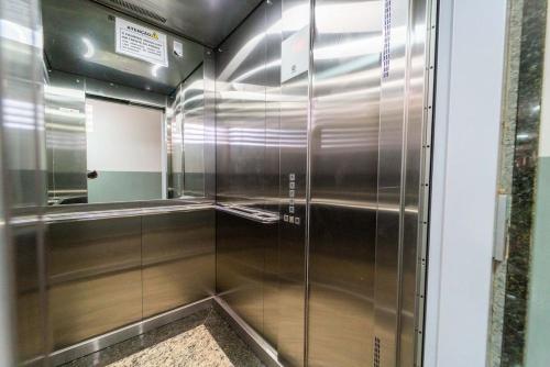 eine ebenerdige Dusche mit Edelstahlwänden und einem Spiegel in der Unterkunft Apartamentos Com Suite ,Wi-Fi 500MB , Estacionamento, Elevador, Cozinha Completa , Jr Catito in Brasilia