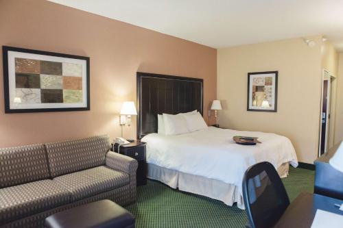 um quarto de hotel com uma cama e um sofá em Hampton Inn Bloomington West em Bloomington