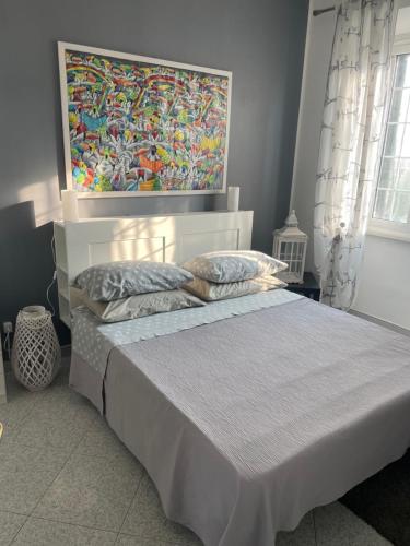 1 dormitorio con 1 cama con una pintura en la pared en Il CASALETTO di Laura, en Fiumicino