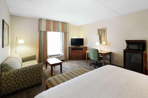 a hotel room with a bed and a couch and a television at Hampton Inn & Suites Blairsville in Blairsville