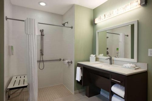 a bathroom with a sink and a shower with a mirror at Home2 Suites Nashville Airport in Nashville