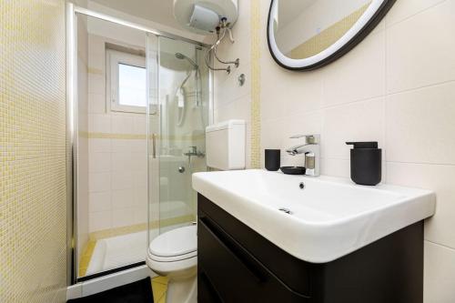 a bathroom with a sink and a toilet and a mirror at Apartman Milazzi in Baška
