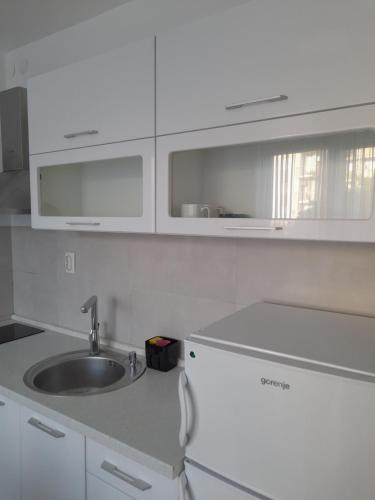 una cocina con armarios blancos y fregadero en Nikola NS en Novi Sad