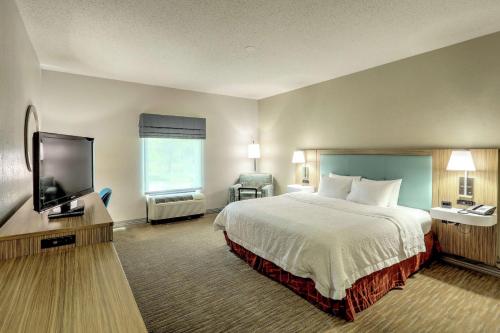 a hotel room with a bed and a flat screen tv at Hampton Inn Batavia in Batavia