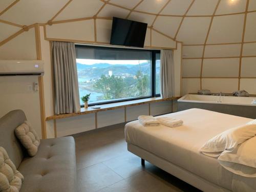 1 dormitorio con cama, bañera y ventana en GLAMPING DO MAR, en Baiona