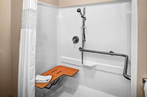 baño blanco con ducha y taburete de madera en Hampton Inn Coldwater, en Coldwater