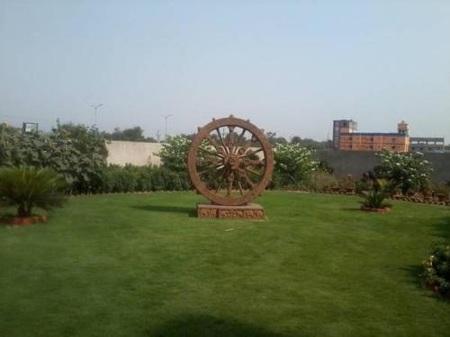 a statue of a wheel in a field of grass at Pipul Utkal Continental in Jhārsuguda