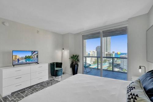 a white bedroom with a tv and a large window at Gorgeous 4 BDRM Condo Stunning Views Beach Access in Hallandale Beach