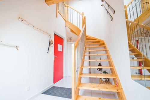 a wooden staircase in a white room with a red door at Apartmán Riviéra Lipno 510/21 in Lipno nad Vltavou
