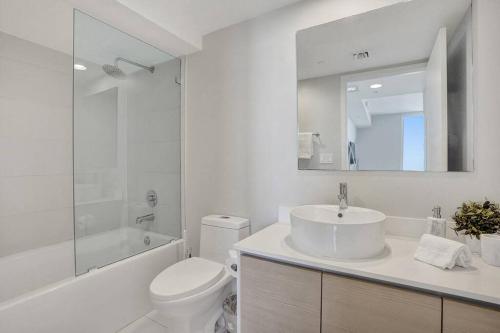 a white bathroom with a sink and a toilet at Perfect Vacation 4 Bedroom Condo Beach Access in Hallandale Beach